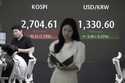 Currency traders work near a screen showing the Korea Composite Stock Price Index…
